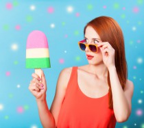 Redhead girl with toy ice cream on blue background.